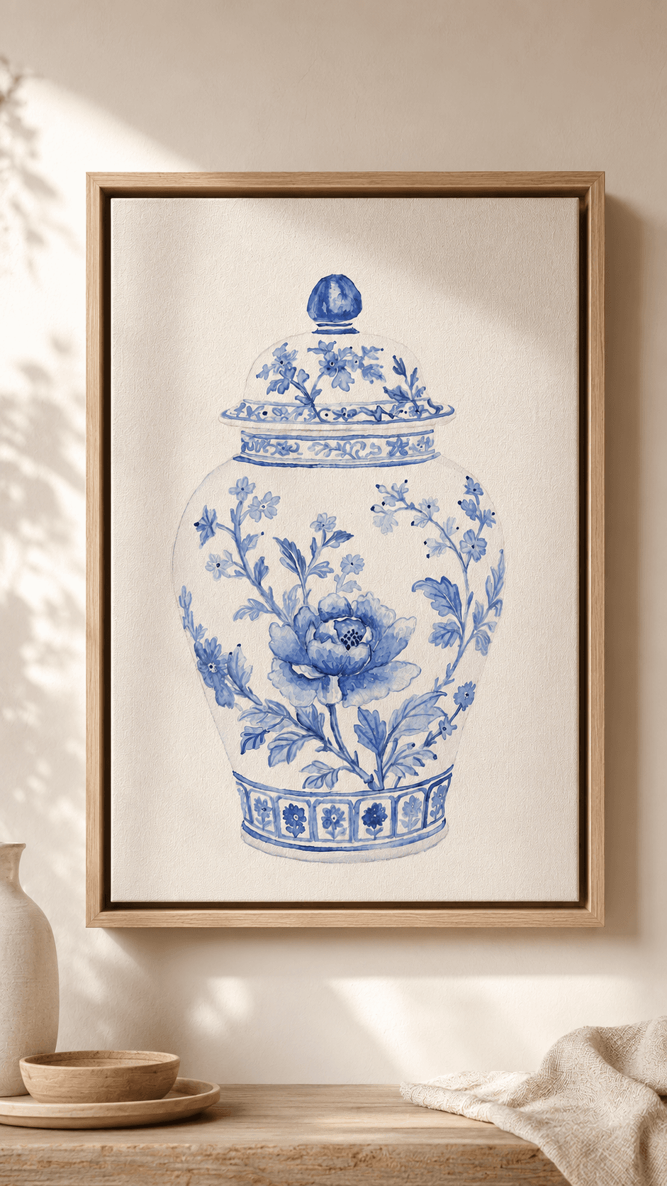 Framed watercolor of a blue-and-white chinoiserie ginger jar painted with peonies and flowering branches, hung on a sunlit plaster wall.